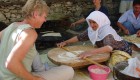 A female tourist sitting across from a local Turkish woman collaborating on cooking