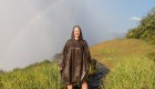 Person standing in a rain poncho in front of a faint rainbow while exploring Victoria Falls in Zambia