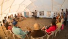 Group of guests in a circle in a canvas tent listening to a whale watching guide explain the anatomy of a gray whale