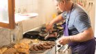 Corsican chef preparing traditional meat dishes during a locally hosted tour experience in Corsica.