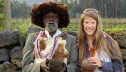 A girl standing next to a man from Rwanda with a green backdrop on a gorilla safari