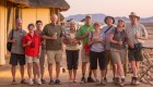 Group of travels in Namibia all holding drinks while standing on a hotel deck in a Namibia desert
