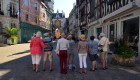 Picture of a line of people with their backs to the camera on a walking tour in a small french town on a sunny day
