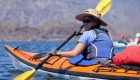 Sea kayakers looking over their shoulder and smiling in front of the islands of Loreto Bay