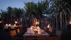 Candlelit outdoor dining setup surrounded by lanterns and wooden fencing in Botswana.