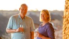 A man and woman smiling at sunset while holding drinks