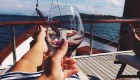 Person reaching out their glass of red wine to cheers while cruising on a small yacht in Croatia on the Mediterranean Sea