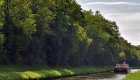 Scenic view of a canal boat cruising through lush green countryside on a sunny day – a peaceful escape for those exploring Canal Boat Tours France.