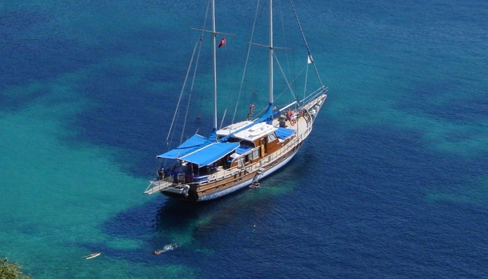 Sail boat with no sails up and a blue deck cover atop the Carian Coast in Turkey